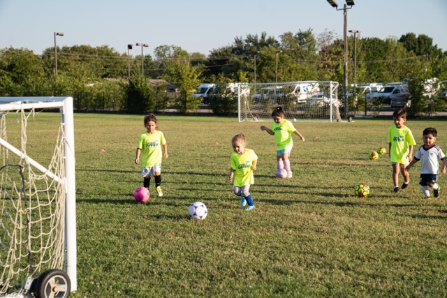 Children practicing dribbling during Little Surfers