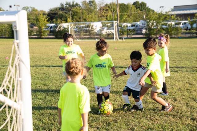 Little Surfers players smiling while competing for the ball